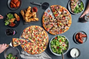 Large spread of pizzas, wings, and sides highlighting Pizza Hut delivery deals.